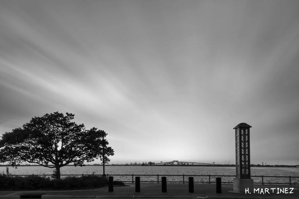 The Unforgiven III, a black-and-white Lake Charles waterfront view with the bridge in the distance.